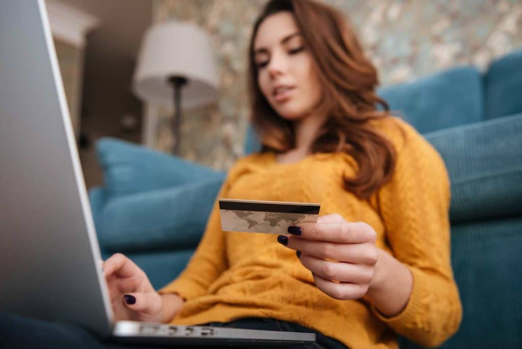 Kvinna vid dator med kreditkort som e-handlar