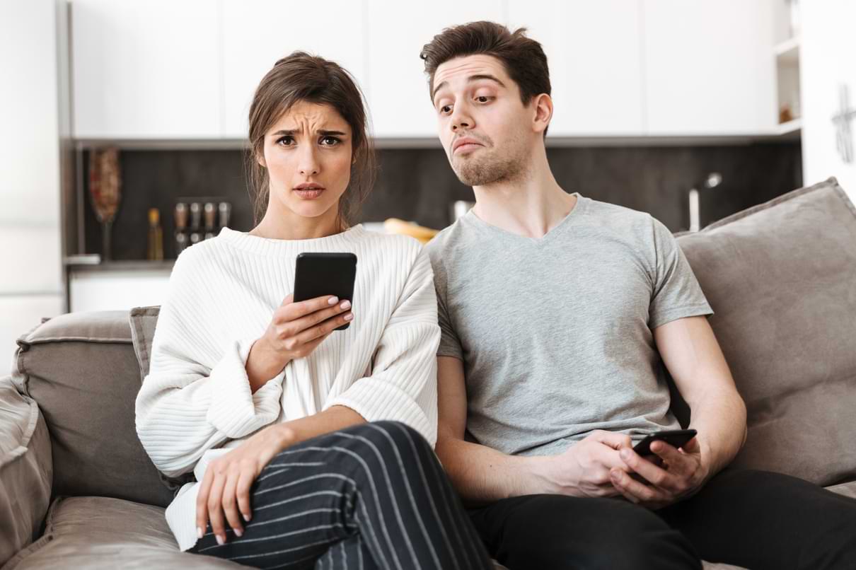 Förvånat par som tittar på mobiltelefon