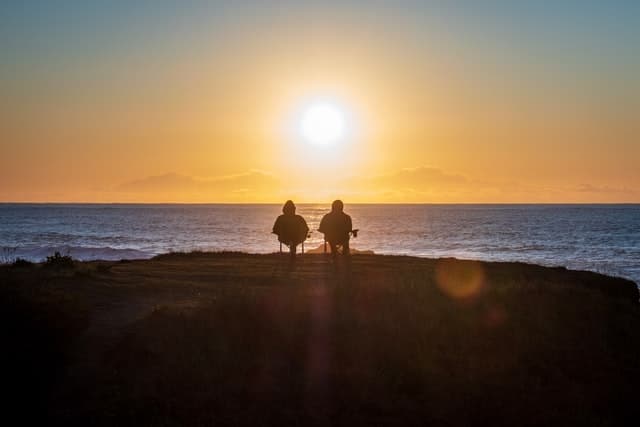 Ett par som sitter och tittar på solnedgången.