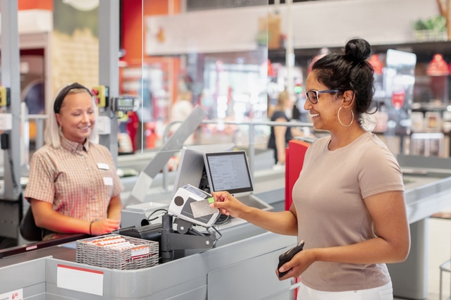 Kvinna betalar i matbutik med ett kreditkort med bonus.