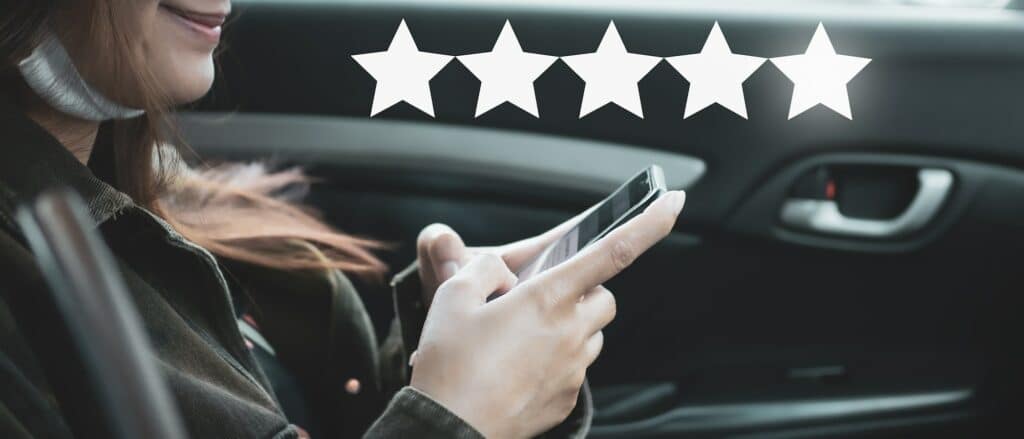 Glad kvinna sitter i en bil med mobiltelefonen i handen, med 5 stjärnor som symboliserar Enkelfinans' höga betyg i recensionen.