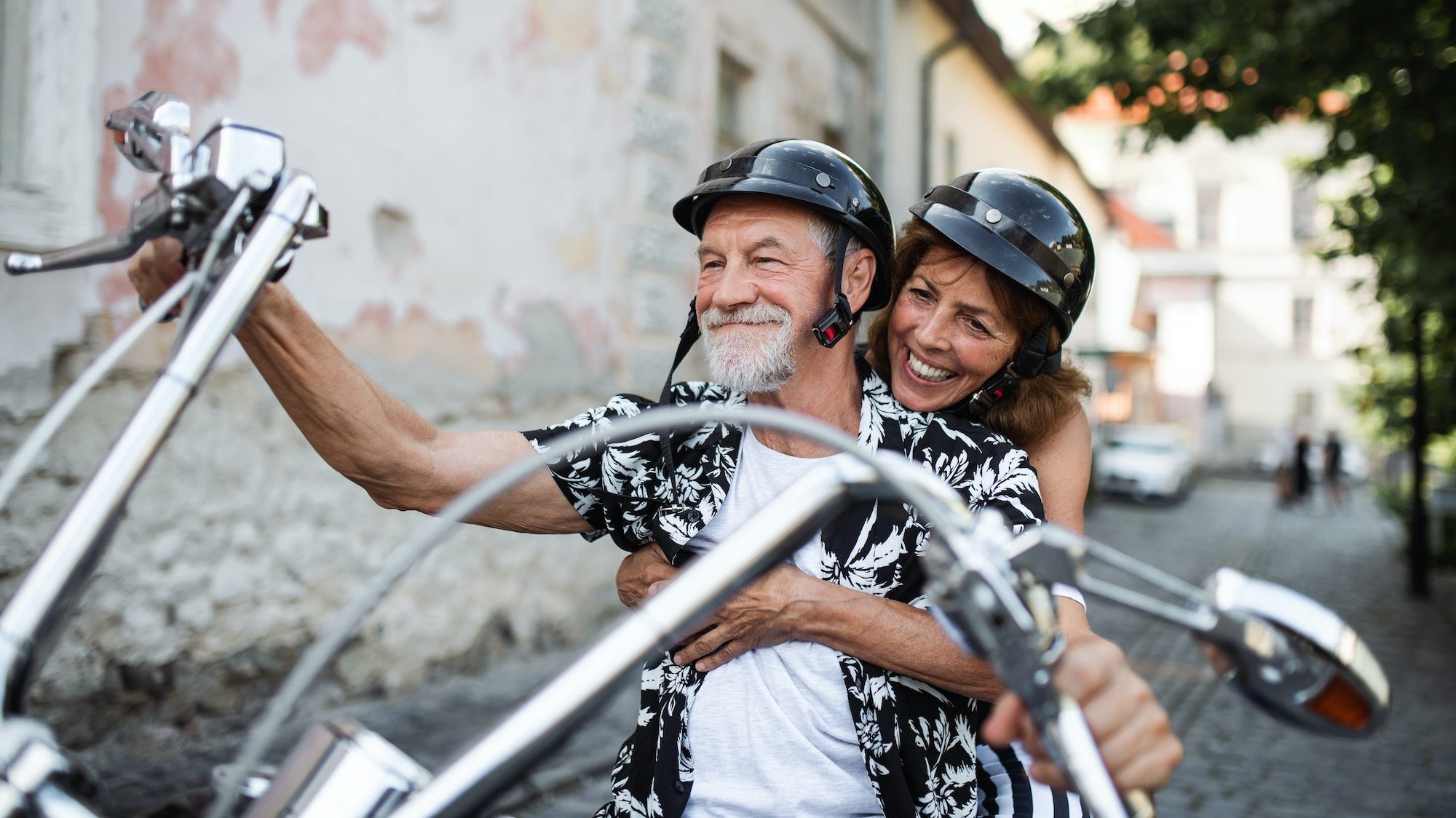 Glada seniora resenärer utforskar staden med motorcykel, finansierad genom mc-lån