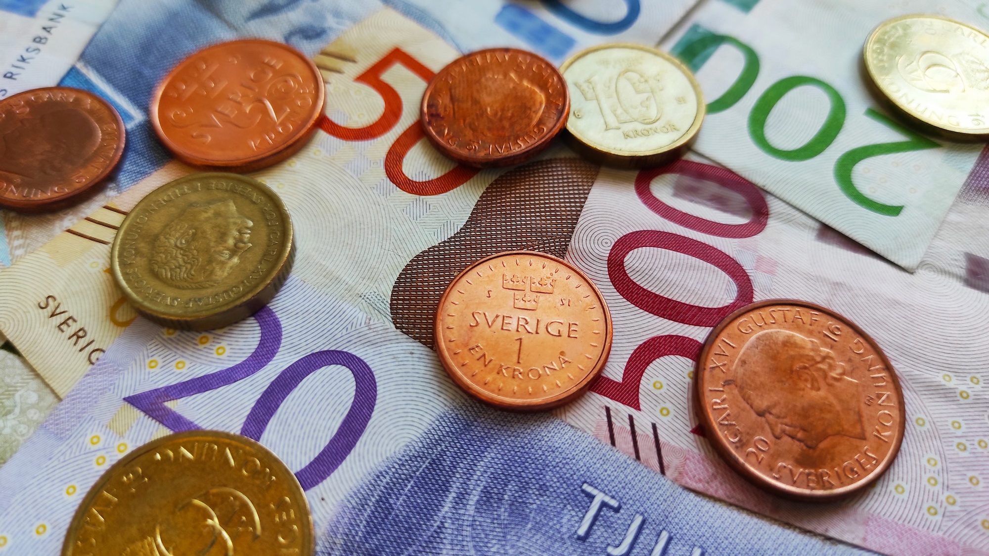 Närbild av svenska mynt placerade på svenska sedlar