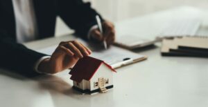 Fastighetsmäklare håller en vit husmodell i handen. Godkännande av bostadslån och tilläggslån